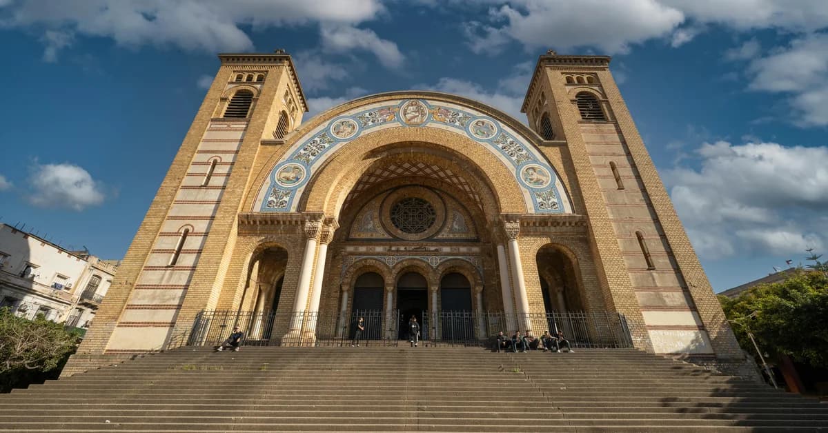 Catedrala din Algeria, cu arhitectură impunătoare, fațadă decorată și trepte largi, vizitată de mai multe persoane.