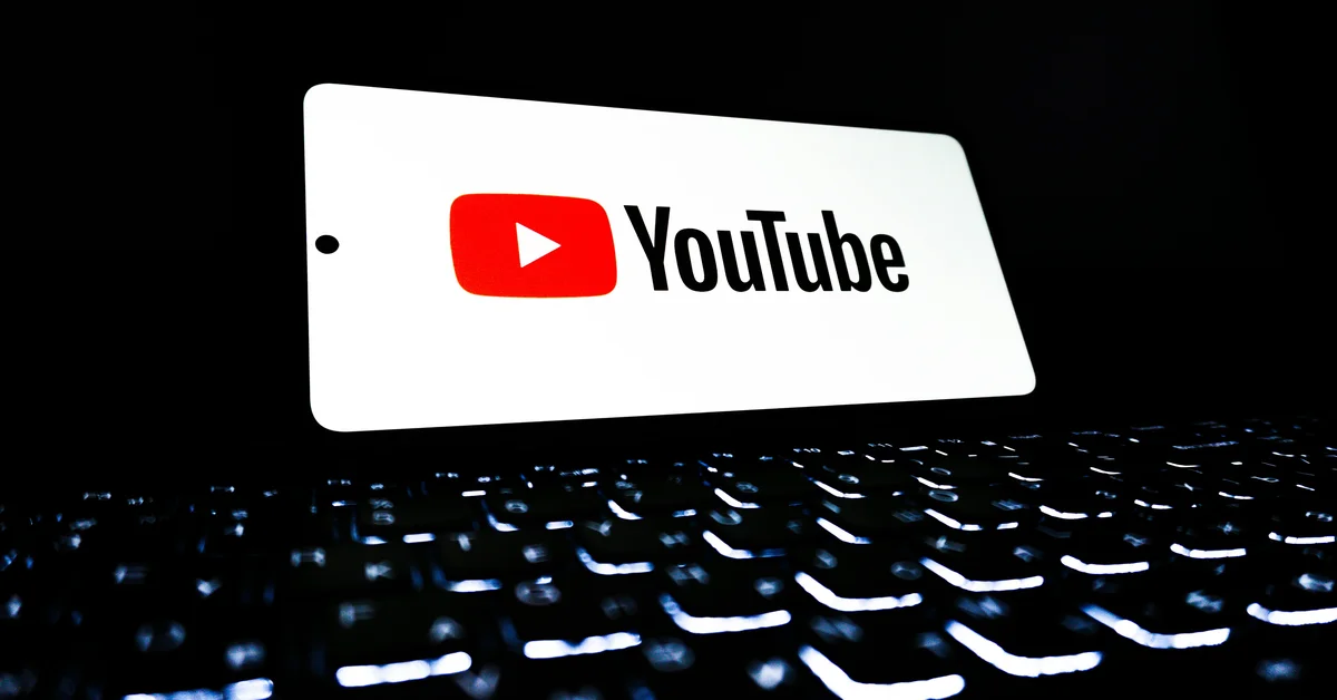 Tastatură luminată în fundal, cu un ecran pe care se afișează logo-ul YouTube.