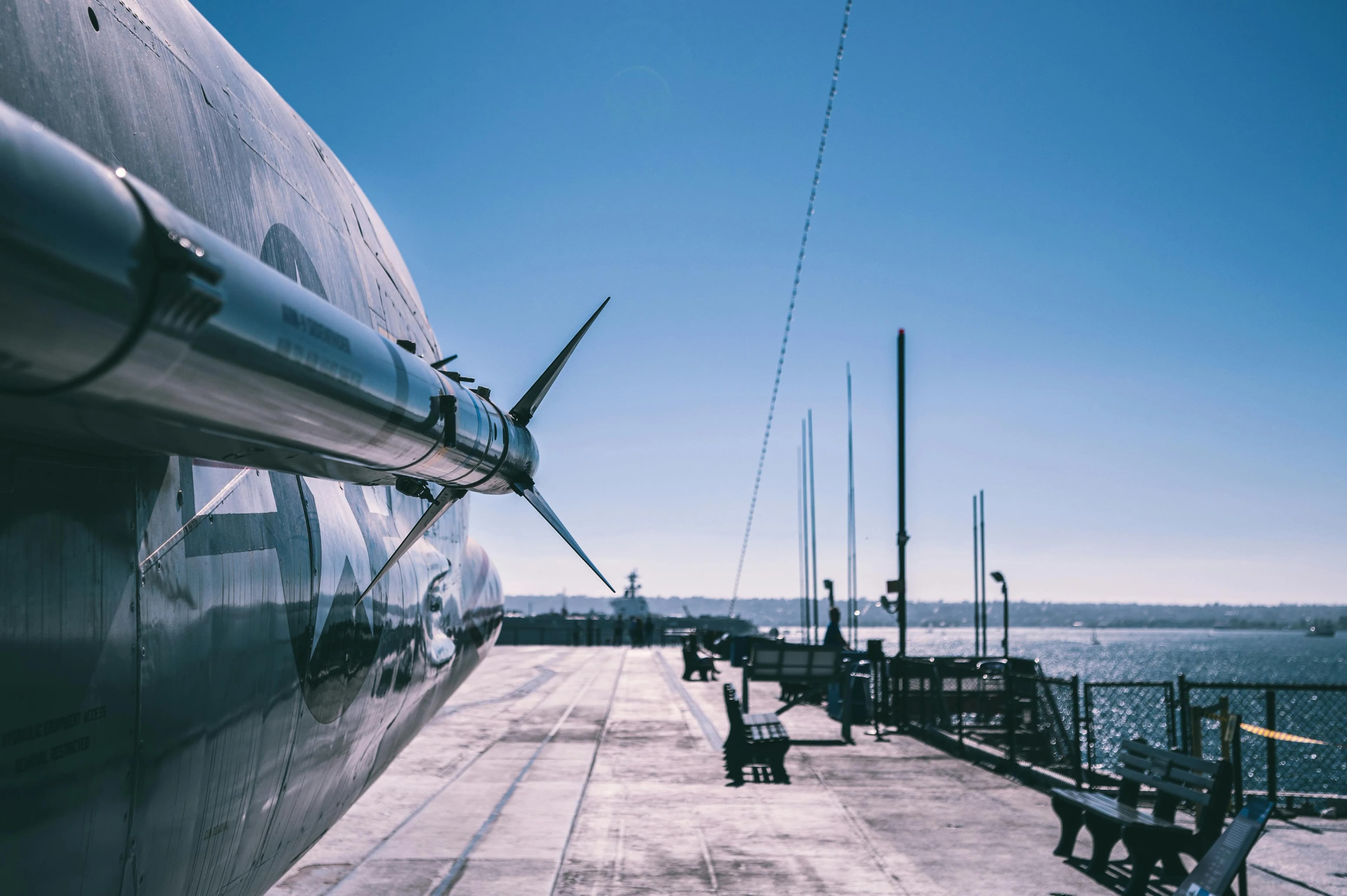 Navă cargo frigorifică albă ancorat în port, cu elice și echipament de stivuire visibl, pe platformă cu catarge și cale de apă în fundal, reprezentând transportul maritim internațional.