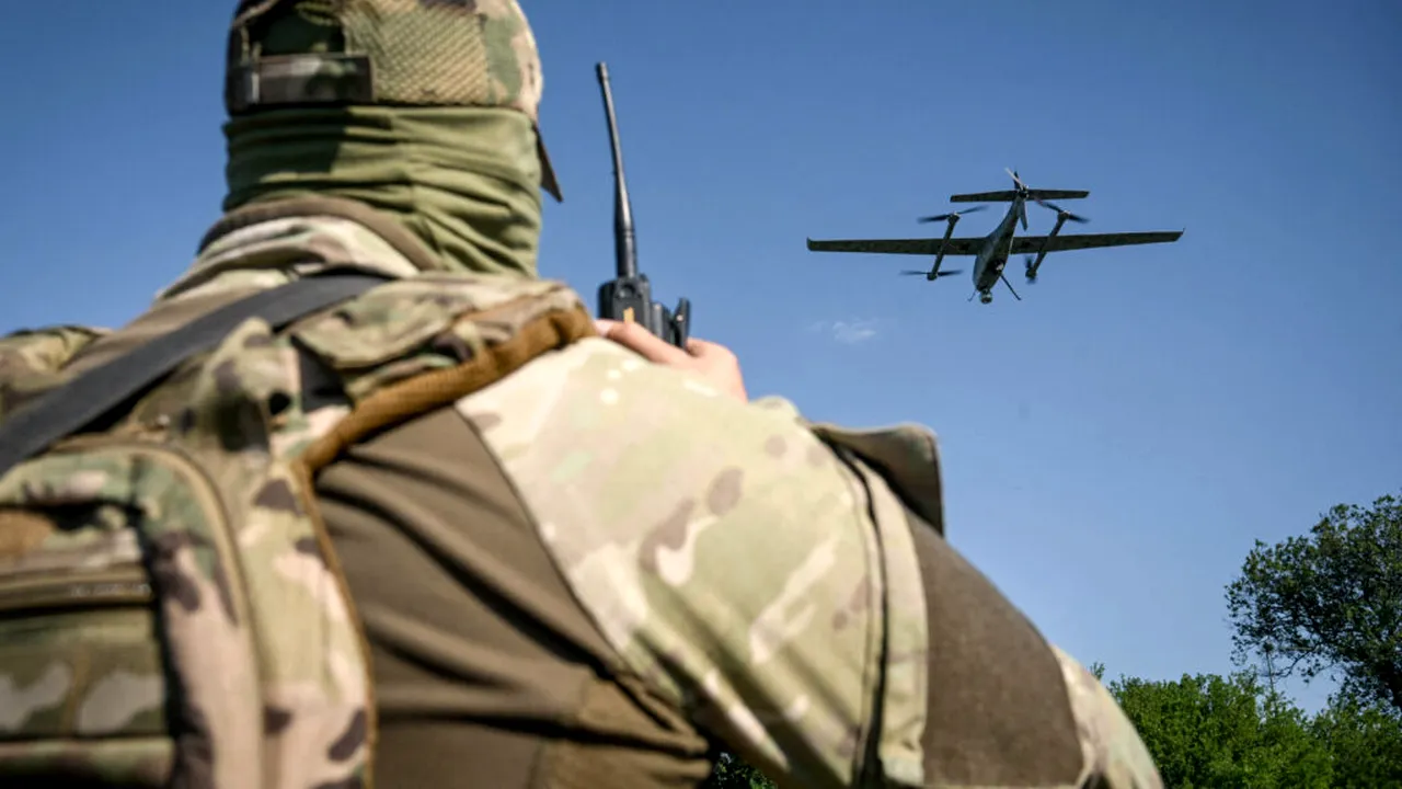 Militar român echipat cu radio de comunicații privind un avion militar în zbor, cu pelin și cer senin în fundal, reprezentând vigilență în contextul alertei aeriene.