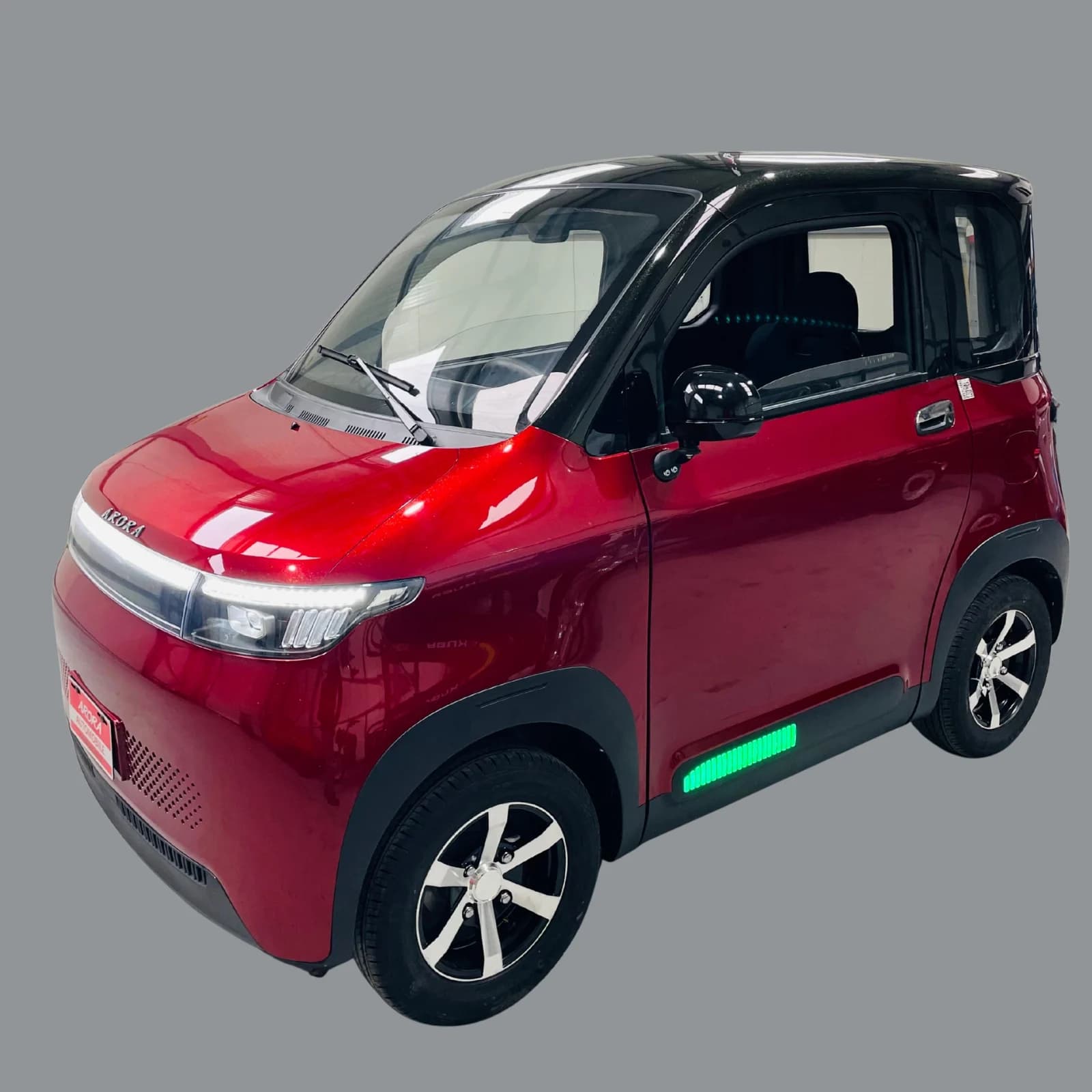 Autoturism electric compact roșu, fotografiat din profil, cu ușă deschisă și bandă luminoasă verde pe flanc, ilustrând vehiculul pentru articolul despre uzura bateriei electrice pe termen lung.