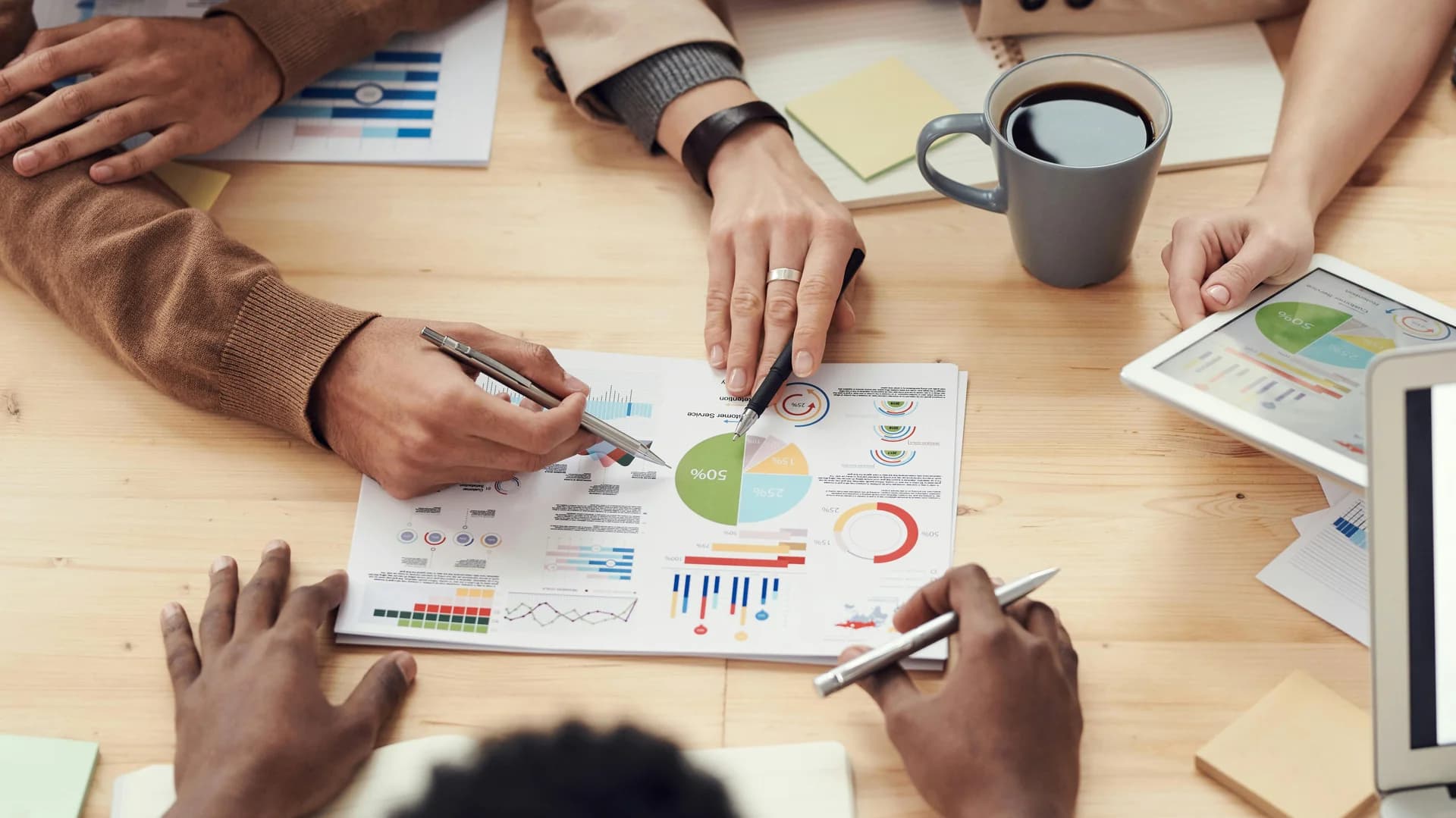Discuție analitică între specialiști asupra unor grafice financiare și diagrame de performanță, ilustrând managementul fondurilor de investiții
